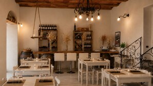 A restaurant with white tables and chairs, wine bottles on shelves, and a chandelier. - Azienda agricola la camporena  (Greve in Chianti)