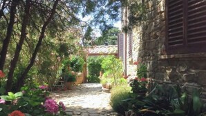 A stone pathway leading to a rustic building with a wooden door and shutters. - Azienda agricola la camporena  (Greve in Chianti)