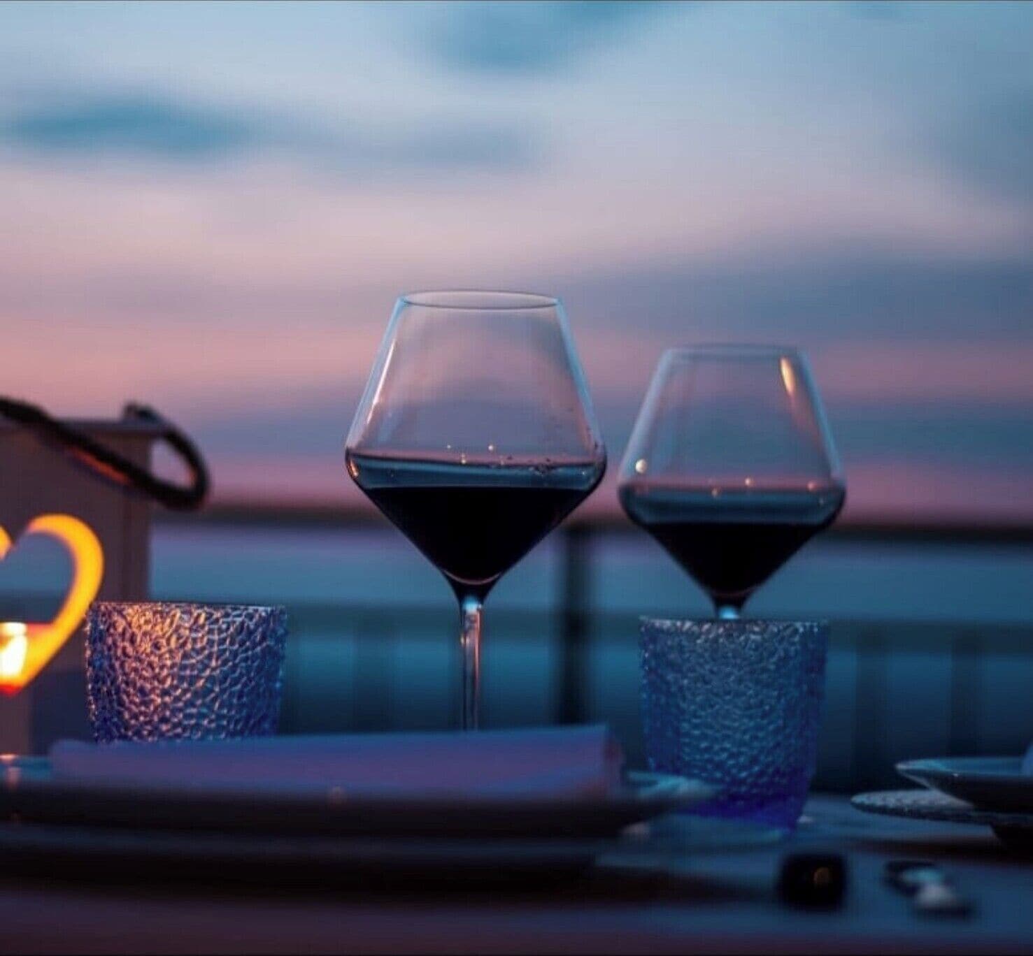 Duas taças de vinho sobre uma mesa, com fundo desfocado.