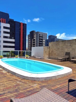 Ein Pool auf dem Dach mit einer Holzterrasse, umgeben von modernen Gebäuden.