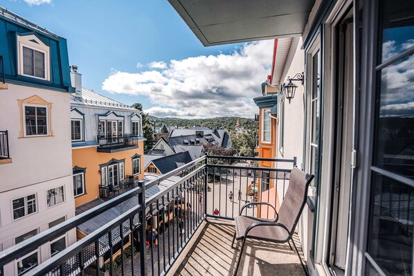 A balcony with a view of neighboring buildings and a clear sky.