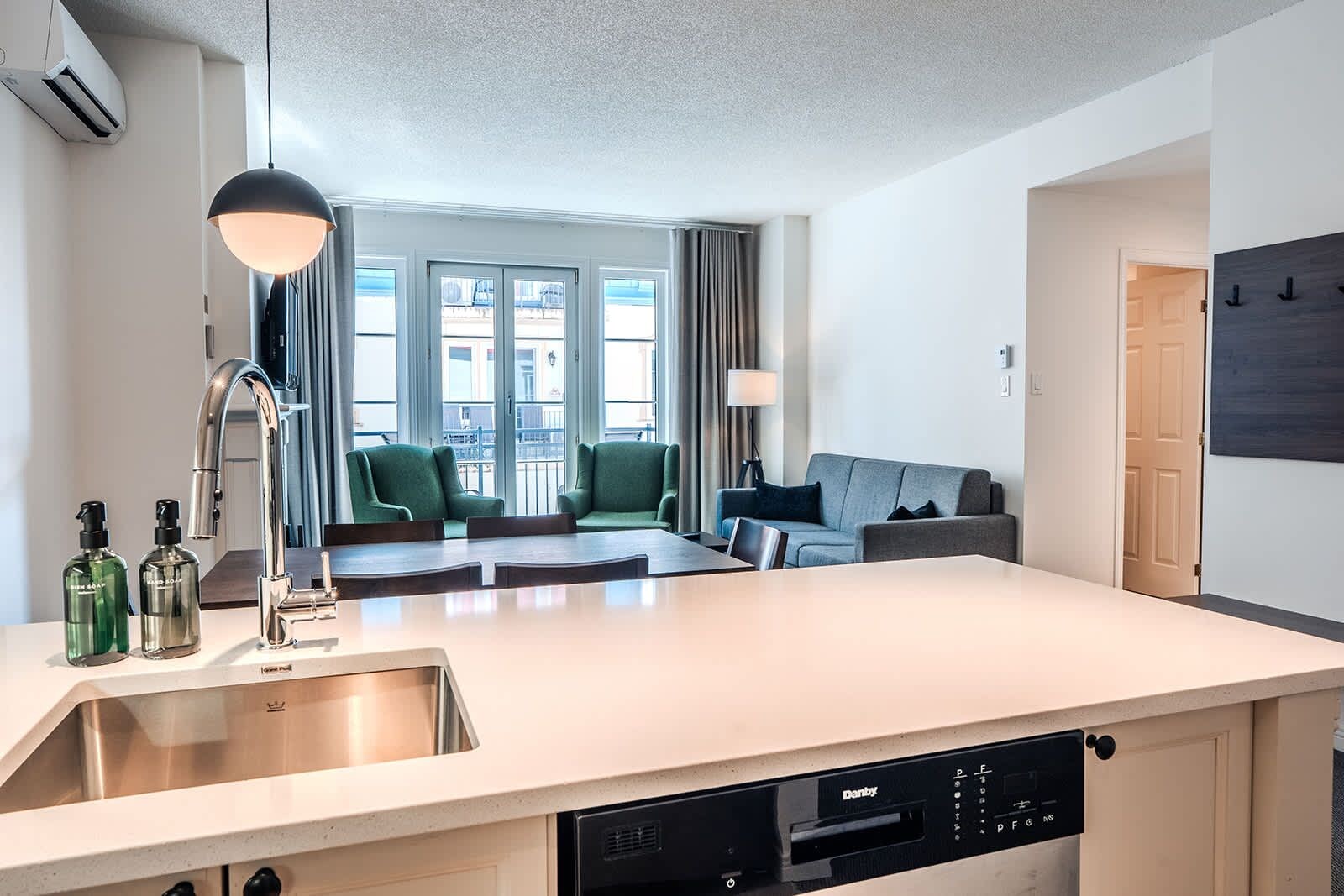 A modern kitchen with a dishwasher, a sink, and a dining area with chairs.