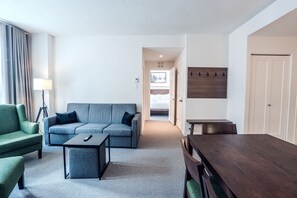 A modern living room with a sofa, a coffee table, a dining table, and a lamp.