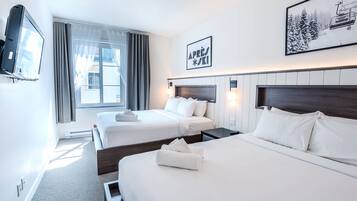 A hotel room with two beds, a television, a window with curtains, and a framed picture on the wall.