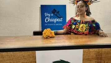 Una persona seduta a una scrivania di legno con un cartello che recita 'Xelva Hostel & Travel Community'.