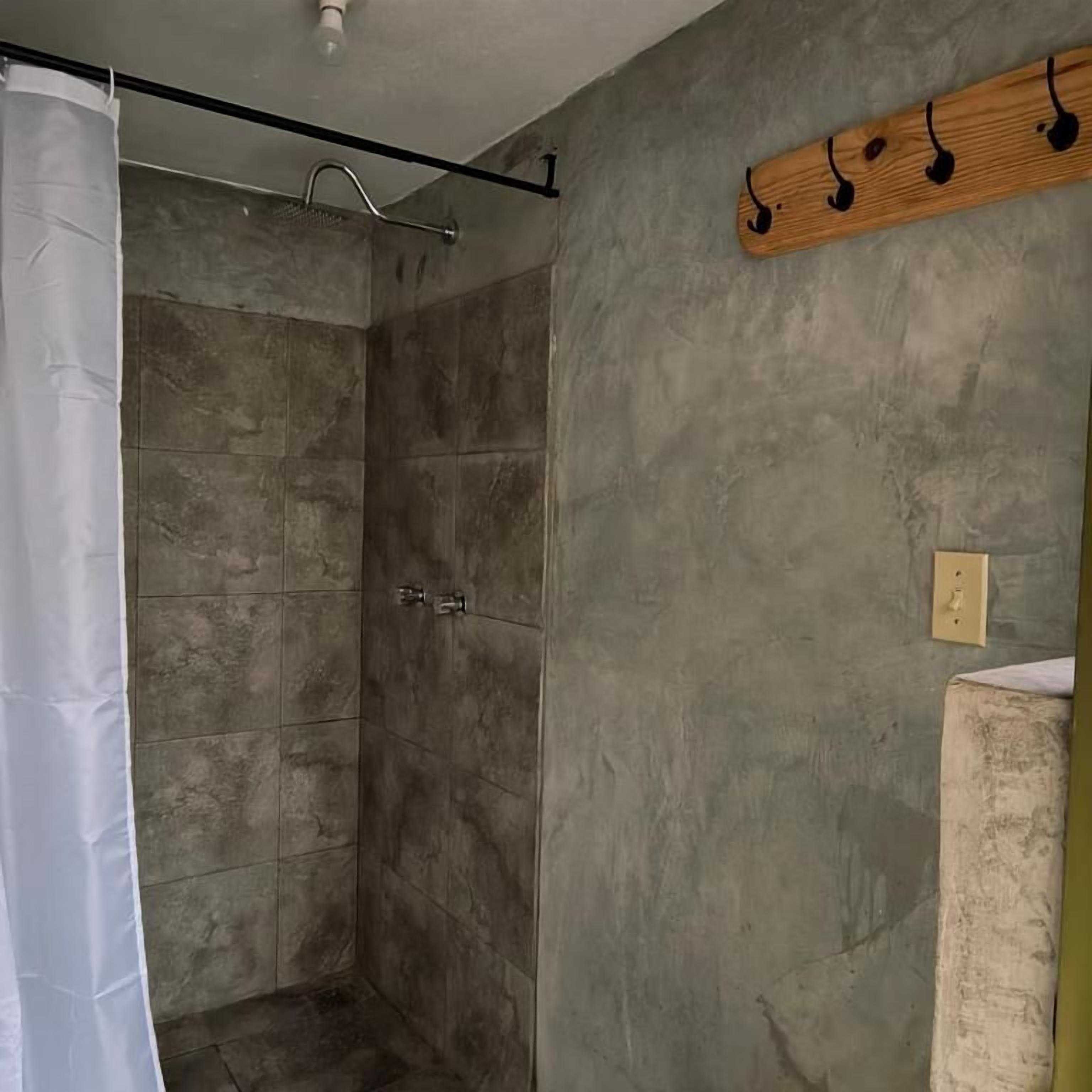 A shower with a curtain, a wooden shelf with musical notes, and a light switch on the wall.