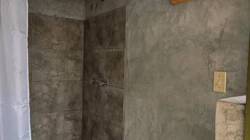A shower with a curtain, a wooden shelf with musical notes, and a light switch on the wall.
