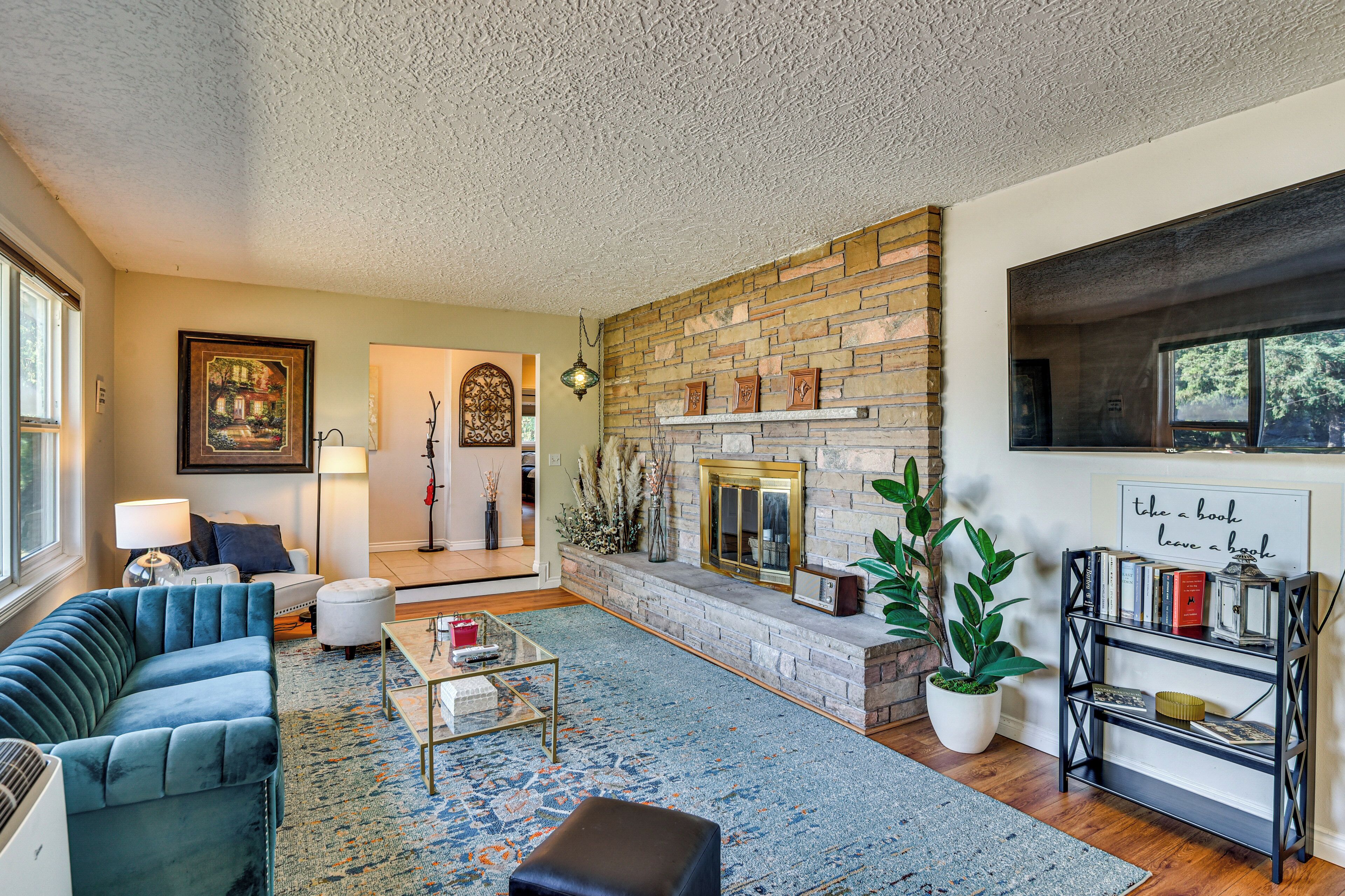 A cozy living room with a blue sofa, a coffee table, a fireplace, and a bookshelf.