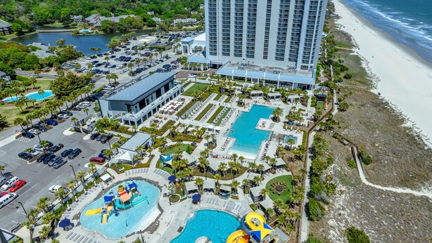A resort with multiple swimming pools, a beach, and a large hotel building.