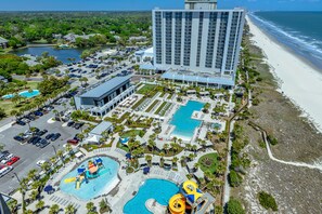 Un resort con varias piscinas, una playa y un gran edificio de hotel.