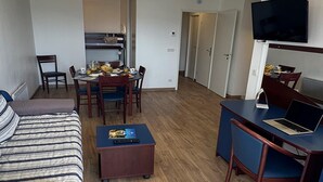 A compact hotel room with a bed, a dining table with chairs, a small desk with a laptop, and a TV mounted on the wall. - Mountain-view 6-persons Apartment (Bolquere)