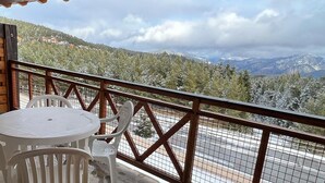 A balcony with a table and chairs, overlooking a mountainous landscape with trees and a road. - Mountain-view 6-persons Apartment (Bolquere)