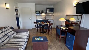 A compact hotel room with a bed, a desk with a computer, a small kitchenette, and a TV. - Mountain-view 6-persons Apartment (Bolquere)