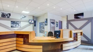 A reception desk with a curved design, a flat-screen TV, and a wall-mounted photo display. - High-altitude Home for 4 (Garin)