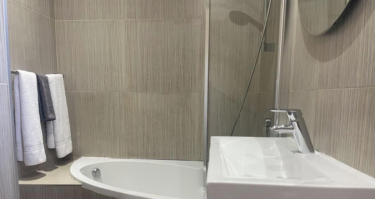 A bathroom with a bathtub, a sink, and a shower area.