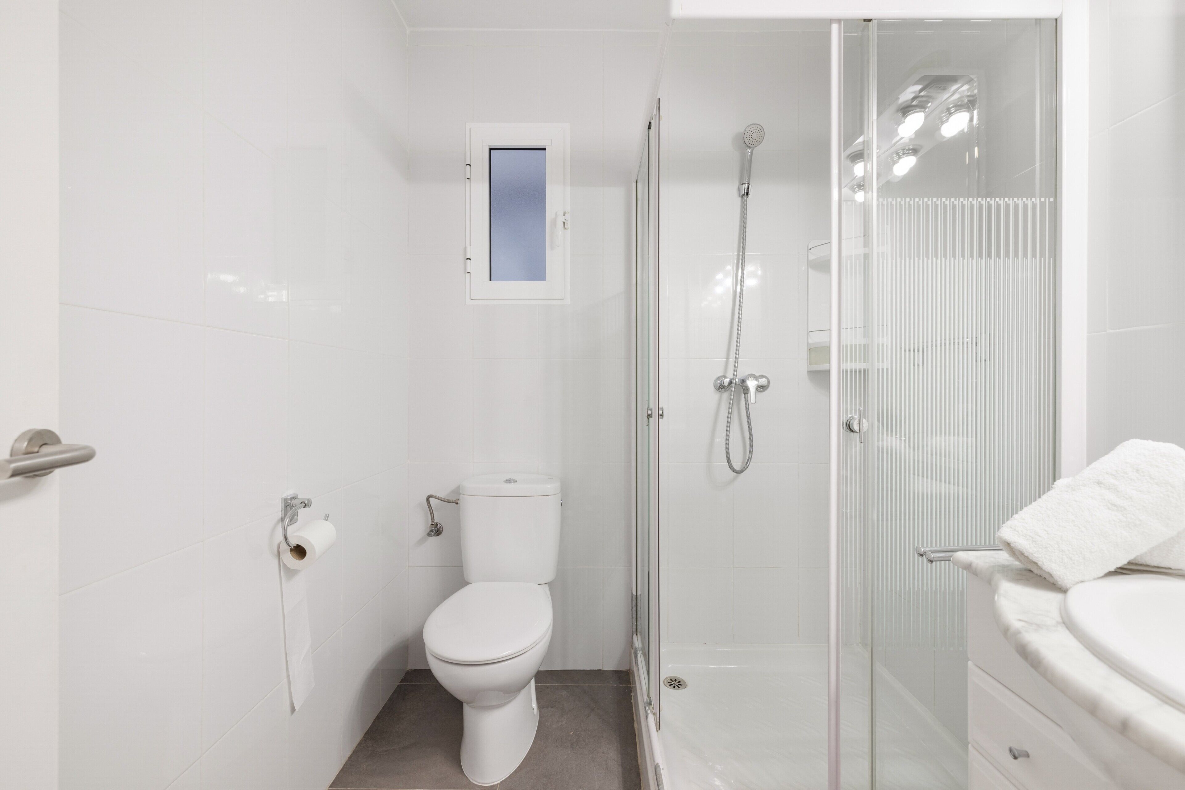 A modern bathroom with a toilet, a glass-enclosed shower, and a white sink.
