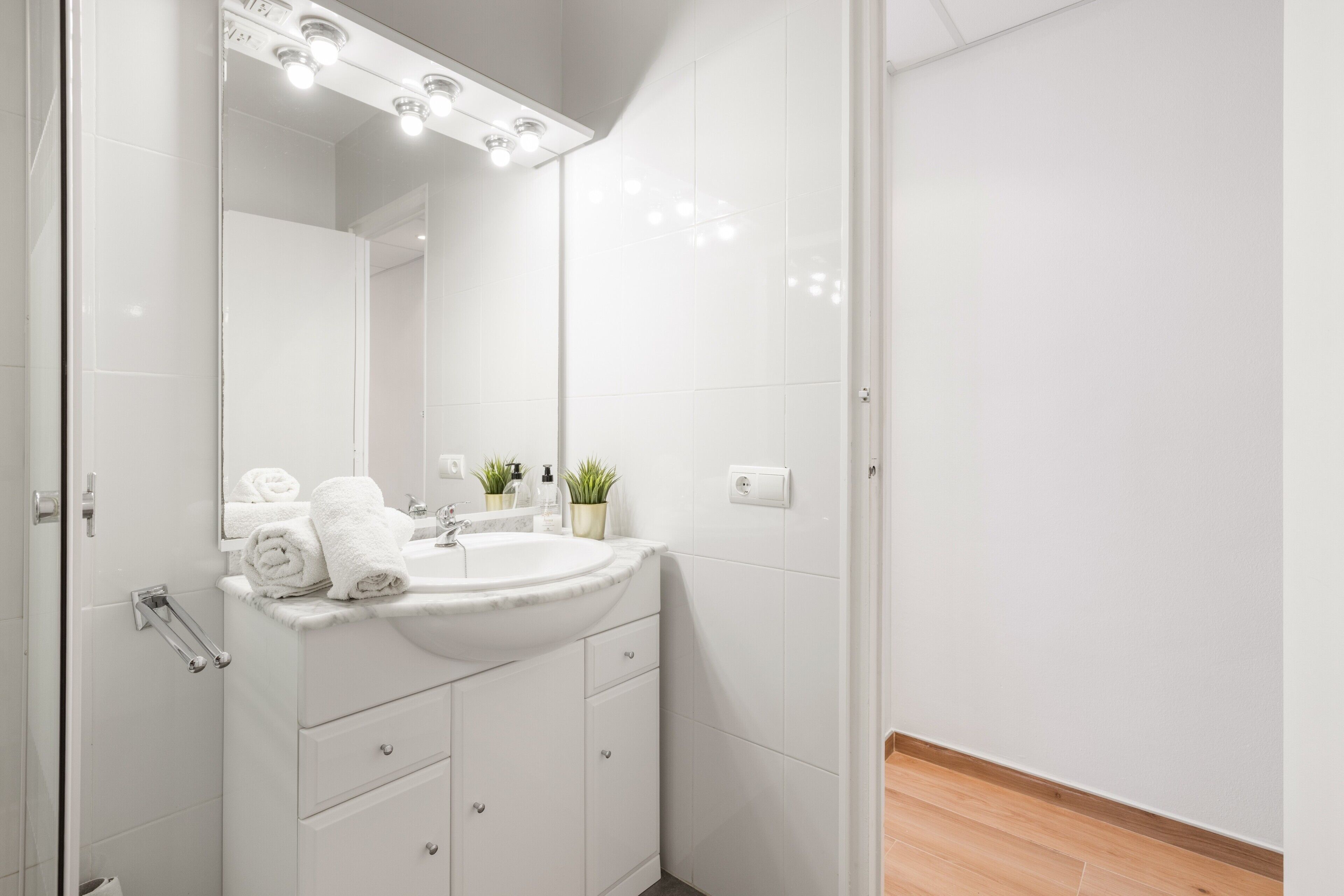 A bathroom with a white sink, mirror, and towel rack.