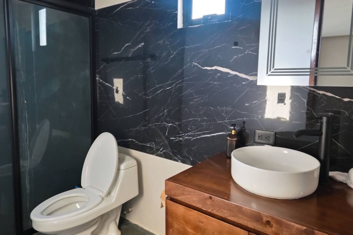 A modern bathroom with a toilet, vanity, and a large mirror.