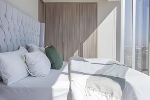 A bedroom with a large bed, a wardrobe, and a view of the city. - Parklife Pabellon (Guadalajara)