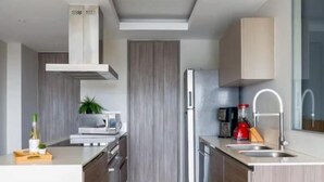 A modern kitchen with a built-in microwave, a stainless steel refrigerator, and a wooden cabinet. - Parklife Pabellon (Guadalajara)