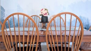 Une table à manger avec des chaises, un vase rempli de fleurs et une vue sur un paysage boisé.