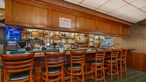 A bar area with wooden cabinets, a 'NO MINORS' sign, a 'HAPPY HOUR' sign, and a variety of bottles on shelves.