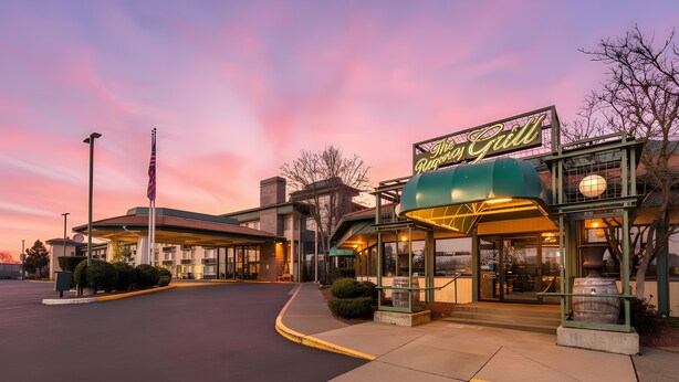 A restaurant with a neon sign, a covered outdoor seating area, and a parking lot.