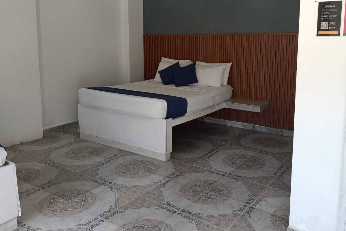 Una cama individual con cabecera de madera, una mesita de noche y un aire acondicionado instalado en la pared.
