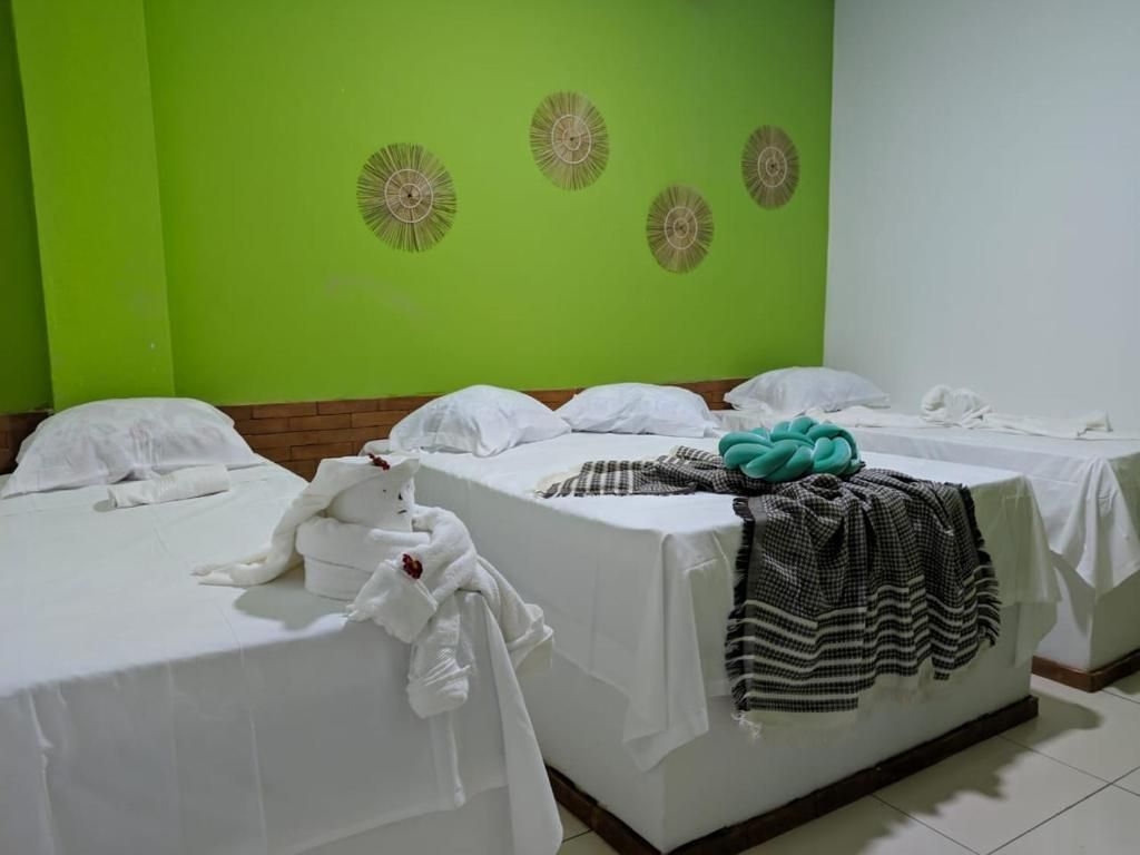 Habitación de hotel con dos camas, cada una con ropa blanca y una manta color turquesa.
