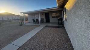 A single-story building with a covered porch, a black door, and a window. - Sweeping Desert & Mountain Views Near Downtown Joshua Tree & JT National Park (Joshua Tree)