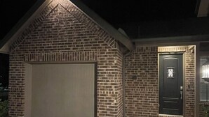 Ett hus byggt av tegel med ett garage, en ytterdörr och en uppfart.