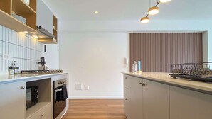 Uma cozinha moderna com forno embutido, bancada de madeira e luminária pendente.
