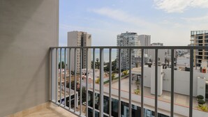 Un balcón con vistas a un paisaje urbano, incluyendo edificios altos y un cielo despejado.
