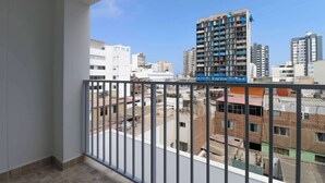 Un balcone con ringhiera in metallo che si affaccia su una veduta urbana con diversi edifici.