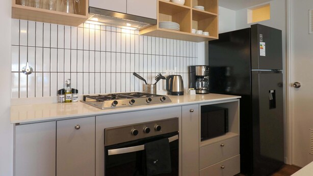 Cucina con fornello, forno, frigorifero ed scaffali con stoviglie.