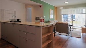 Una cucina moderna con isola centrale, zona pranzo con divano e tavolo, e un'ampia finestra con vista sulla città.