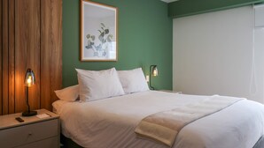 Una camera da letto con un letto, comodini, una lampada e un quadro appeso al muro.