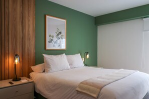 A bedroom with a bed, bedside tables, a lamp, and a framed picture on the wall. - w* | Curated Urban 2BR w/ Balcony in Miraflores (Miraflores)
