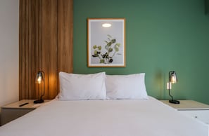 A hotel room with a bed, two bedside lamps, a framed picture on the wall, and a wooden panel on the wall. - w* | Curated Urban 2BR w/ Balcony in Miraflores (Miraflores)