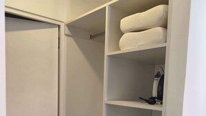 Un armadio bianco con diversi ripiani e cassetti, un portascarpe appendibile e un piccolo elettrodomestico sullo scaffale superiore.
