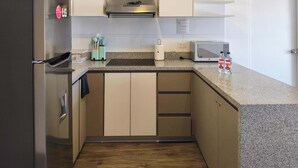 Una cucina moderna con frigorifero in acciaio inossidabile, forno a microonde e tostapane. Il pavimento è in legno e lo sfondo dietro il piano cottura è rivestito di piastrelle bianche.