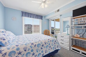 Ein Schlafzimmer mit Bett, Schminktisch, Fernseher und Balkonblick.