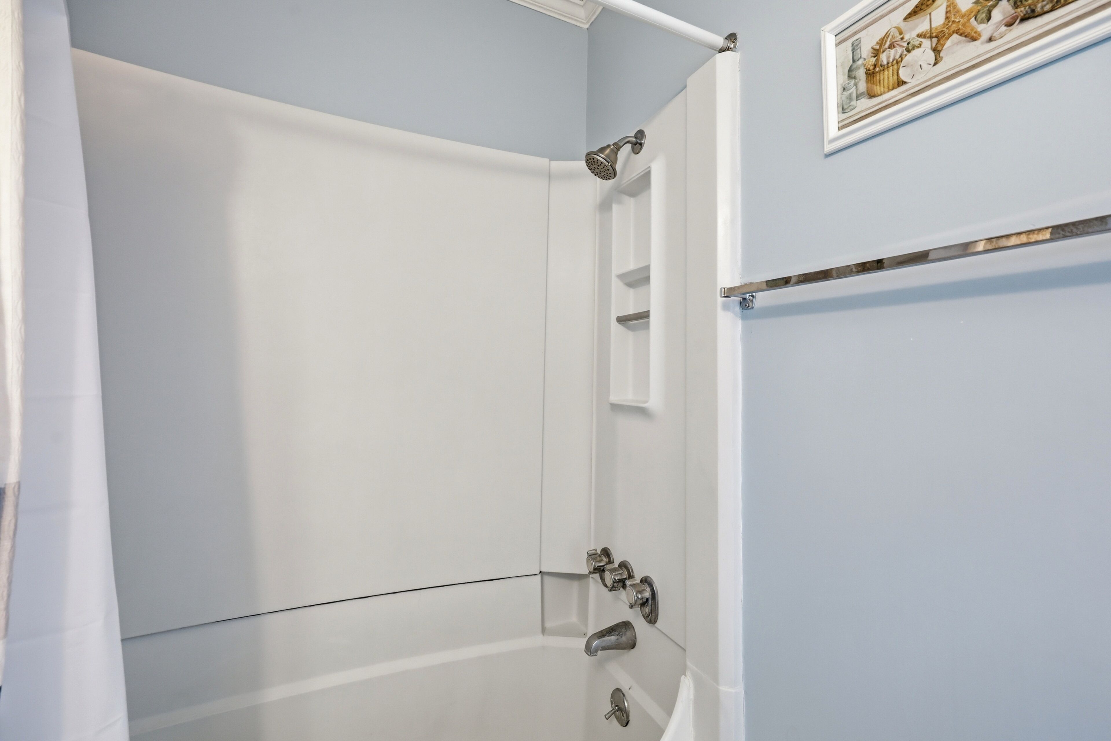 A bathroom with a bathtub, a shower, and a towel rack.