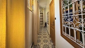 Un pasillo con piso estampado, puertas de madera y una reja decorativa de metal.
