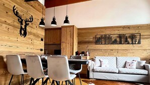 Ein modernes Interieur mit Essbereich, einer Couch, Holzwänden und Deckenbalken.
