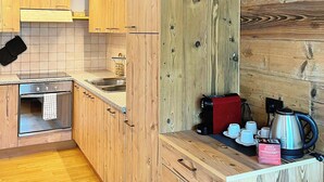 Eine moderne Küche mit Holzschnitzereien, einem eingebauten Backofen, einer Spüle und einer Kaffeemaschine.