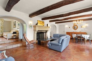 A spacious living room with a fireplace, a dining area, and a view through an archway.