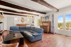 Ein Wohnzimmer mit Ecksofa, Couchtisch, Holzschrank und einem großen Fenster mit Blick.