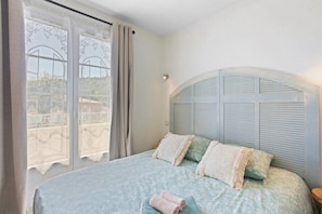 A bedroom with a large bed, a window with curtains, and a headboard with shutters. - Lavender Cottage, residence with pool (Callian)