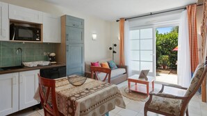 Une cuisine moderne équipée d’un four à micro-ondes, d’un évier et de placards, un coin repas avec une table et des chaises, un canapé et une porte-fenêtre coulissante donnant sur un espace extérieur.